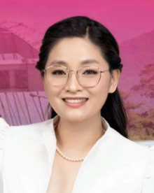 A bespectacled Guo wearing a white top and a pearl necklace.