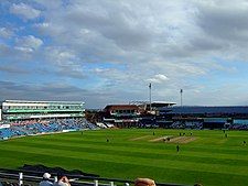 A panoramic view of a cricket ground with players occupying the field