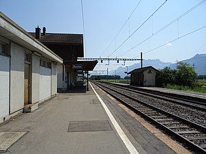 Double-tracked railway line with two-story station building on the left