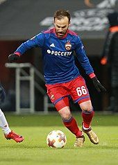 A photograph of a man in blue and red association football attire.