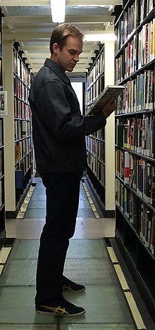 Rugg holding books in a library