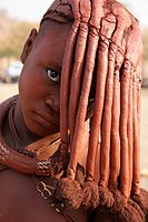 Pubescent Himba girl with hair headdress styled to veil her face