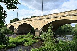 Stone bridge over a river with greenery on both banks