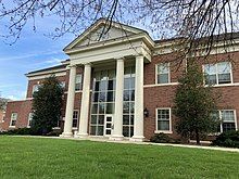 Two-story red brick building with four large white columns at the entrance.