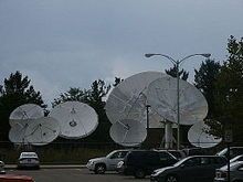 A group of satellite dishes as seen from a parking lot