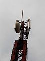 Close-up of a base station antenna in Mexico City, Mexico. There are three antennas: each serves a 120-degree segment of the horizon. The microwave dish links the site with the telephone network.