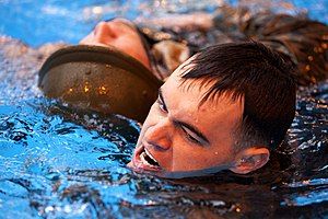 Photograph of a man swimming and performing a practice rescue of another, who is floating