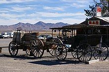 Two wagons in front of a wooden building with a surrounding patio.