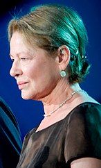 Profile of a woman wearing a brown blouse and a blue earring.