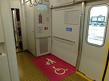 Wheelchair space at the end of a Japanese train with the floor painted pink to improve visibility