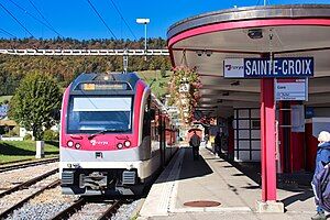 Pink train next to a station sign and shelter