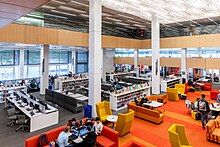 university library with bright lights and students working in groups at tables