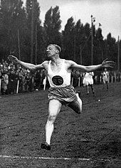 Photo of Tinus Osendarp holding his arms wide at the finish line with an audience in the background