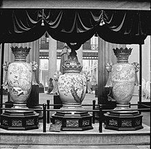 The three vases in a display area with a plaque