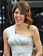 A photo of a brown-haired woman wearing a white dress.