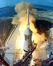 The swing arms move away and a plume of flame signals the liftoff of the Saturn V launch vehicle.