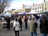 people walking in front of gazebos with some buildings as a background.