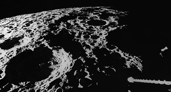 View of the west rim of the basin while at the sunset terminator during the Apollo 16 mission. Spencer Jones is in the lower left, and the spacecraft's gamma-ray spectrometer is in lower right.