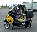 A picture from the side through the cockpit areas of several BMW C1 scooters which are parked side by side in perfect alignment