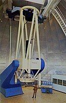 A large telescope in an observatory with a man standing beneath it.