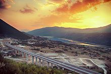 A sunset with mountains and a highway as a focus of the image