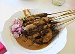 Sate, a popular Indonesian dish featuring skewered and grilled meat, served with a savory peanut sauce. Originating from Java, its popularity has increased across Southeast Asia.