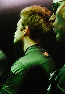 Headshot of JerAx, wearing his team's green uniform, facing away from the camera, looking towards the left