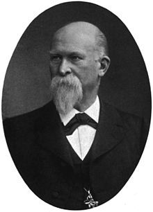 Portrait of Franz König, a Victorian man with a beard and moustache, wearing a black jacket, white shirt, black tie