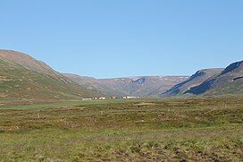 A grassy plain with stubby mountains rising on either side