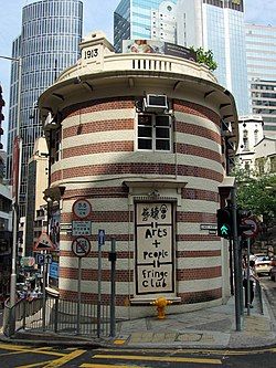 A view of the curved, striped end of the South Block from Glenealy, with the words "Arts and people—Fringe Club" painted over a bricked-up window.