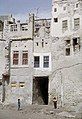 The image shows two houses within Qatif Castle, each consisting of three floors with a corridor between them and a basement underneath. The photograph was taken in 1975.