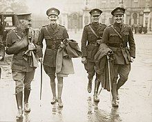 a group of four males in uniform walking along a street