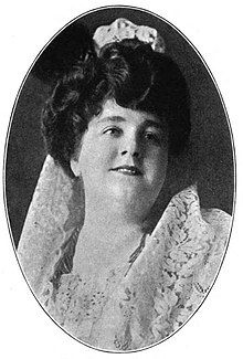 A white woman with dark hair and a round face, wearing a white lace mantilla.