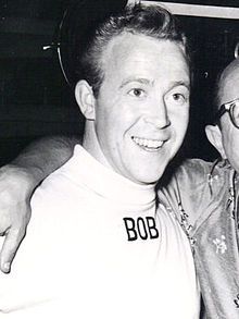 A monochrome photo of an American man wearing a white shirt with "BOB" on it.