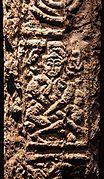 A figure, perhaps cross-legged and horned, on the north cross at Clonmacnoise.