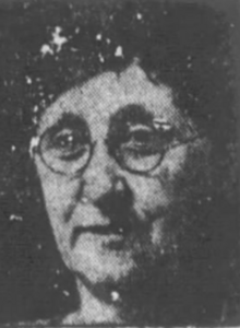 A black-and-white photograph of a white woman's face; she is wearing round eyeglasses