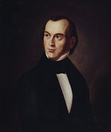 A young man in early nineteenth-century formal dress: a black coat and a white shirt. He has a slightly receding hairline, a pale face and dark hair.