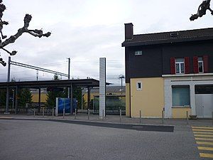 Two-story building with gabled roof next to canopy-covered platform