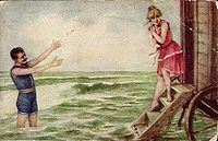 Man and woman in swimsuits, c. 1910. The woman is exiting a bathing machine. Once mixed-sex bathing became socially acceptable, the days of the bathing machine were numbered.