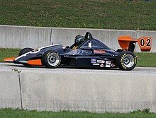 a small open wheeled race car with large aerodynamic wings