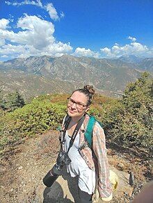 Woman holding camera in mountain landscape.