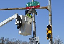 City worker installing a “N3RD St” sign at the intersection with Spring Garden Street