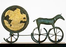 A sculpture of the sun in a chariot being pulled by a horse that has wheels instead of hoofs.