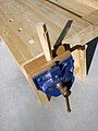 A bench vise with its dog extended, holding (without using the dog) a wooden bench dog being worked