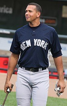 A man in a navy blue baseball jersey and gray pants