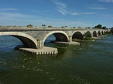 a modern colour photograph of a multi-arched bridge over a broad river