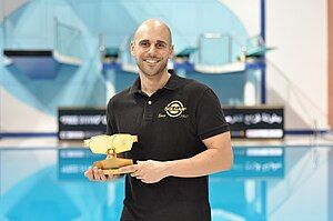 Goran Čolak smiling and holding a trophy.