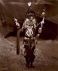 Navajo man in ceremonial dress with mask and body paint, c. 1904