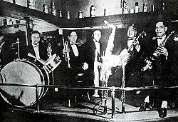 Barbarin, left, plays drums with a band on Rampart Street in New Orleans, 1919. Also pictured are (left to right): Arnold Metoyer, trumpet; Luis Russel, piano; Willie Santiago, banjo; Albert Nicholas, saxophones and clarinet.