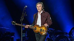 Paul McCartney holding a guitar on stage